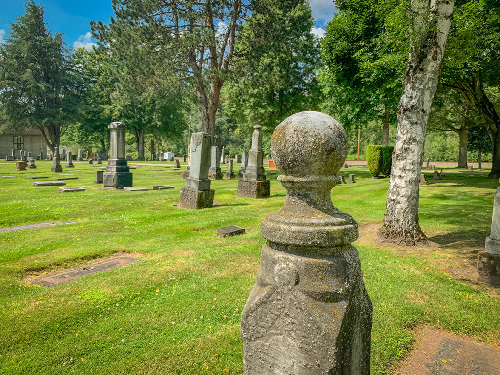 Stone markers, trees and grass in the Pioneer Cemetery.